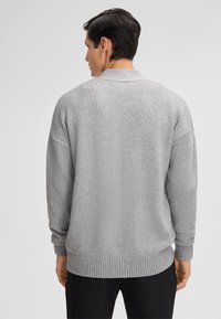 Grauer Strickpullover mit lässiger Passform, gerippten Bündchen und Saum sowie einer subtilen Textur. Die Rückseite hat ein minimalistisches Design ohne zusätzliche Details.