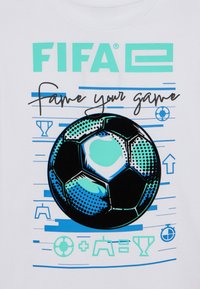 Biely tričko s grafickým dizajnom čierneho futbalového lopty, tyrkysovým textom FIFA a modrými akcentmi s ikonami a textom súvisiacim so hrou.