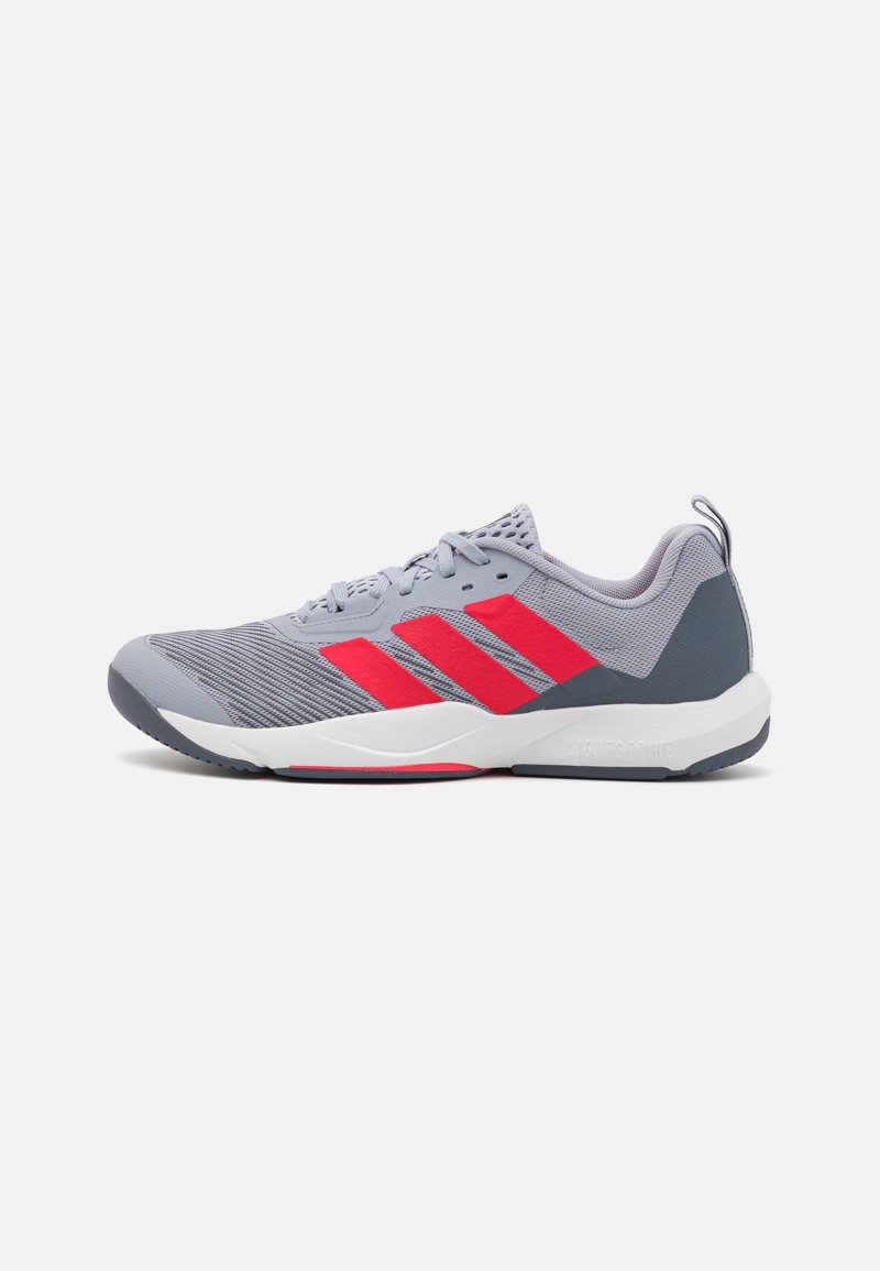 Gray athletic shoe featuring red accents and three stripes. Made of mesh and synthetic materials with a textured surface and rubber sole.
