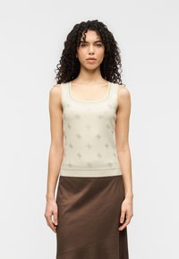 Μπλούζα τύπου τοπ σε κρεμ απόχρωση με τετράγωνο ντεκολτέ, διακοσμημένη με διακριτικό λουλουδάτο μοτίβο. Το ύφασμα είναι απαλό, εφαρμοστό, συνοδευόμενο από καφέ φούστα.