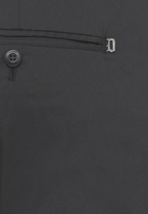 Primo piano di tessuto nero con un piccolo bottone con la scritta "Dondup" e il bordo di una tasca cucita con un ciondolo in metallo a forma di lettera "D".