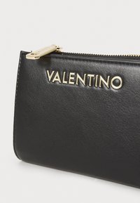 Black leather clutch bag featuring a textured finish and a gold-tone zipper pull. "VALENTINO" logo embossed on the front.