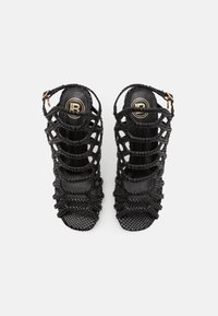 Svarta högklackade sandaler i vävt material, med öppen tå-design, flera remmar och en rem med ett guldtonat spänne.