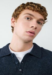 Granatowa, teksturowana koszulka polo z miękkiej mieszanki wełny, z kołnierzykiem zapinanym na guziki i trzema pasującymi guzikami przy dekolcie.