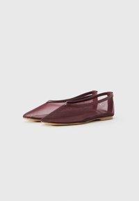 Un paio di ballerine piatte, con punta a scomparsa, in mesh color maroon, con sottile bordo e suole beige su uno sfondo semplice.