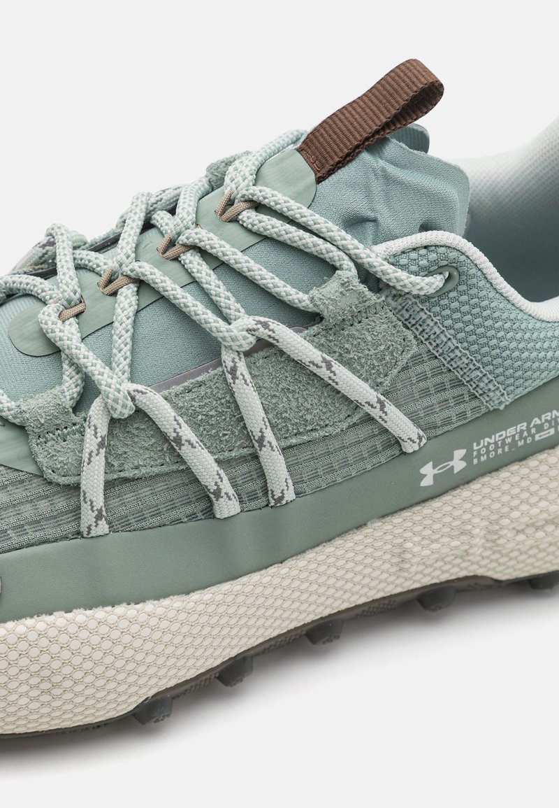Bottine de sport vert clair avec des textures mélangées, y compris un tissu lisse et des accents doux, dotée d'une semelle à motifs et de lacets élastiques.