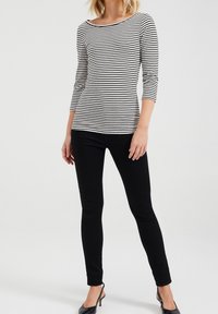 Svart- och vitrandig långärmad topp med rundad halsringning, i kombination med svarta slim fit byxor och svarta högklackade skor.