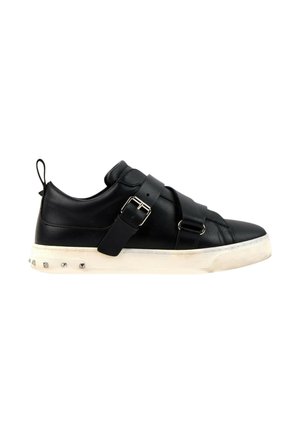 Sort læder-sneaker med brede remme og spænder, hvid sål med metalnitter og hæl-loop, vist fra siden.