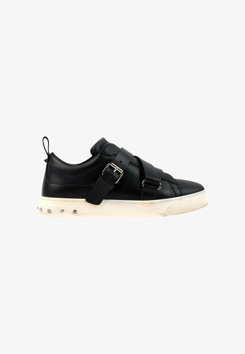 Baskets en cuir noir avec larges sangles et boucles, semelle blanche avec clous métalliques et languette de talon, vues de côté.