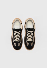 Baskets noires et dorées avec un upper scintillant, des accents en daim beige et des lacets beiges. La semelle est en caoutchouc texturé.