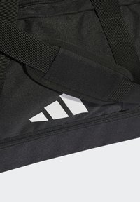 Borsa duffle nera con logo a tre strisce bianche. Presenta un tessuto resistente, cinghie robuste e un compartimento con cerniera per una conservazione sicura.
