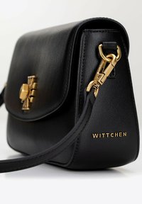 Borsa a tracolla in pelle nera con dettagli dorati, superficie texturizzata, chiusura a patta piatta e emblema con marchio. Presenta una tracolla removibile.