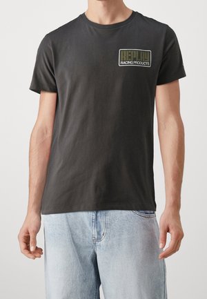 Czarna bawełniana koszulka z okrągłym dekoltem i krótkimi rękawami. Logo w oliwkowej zieleni umieszczone na lewej piersi.