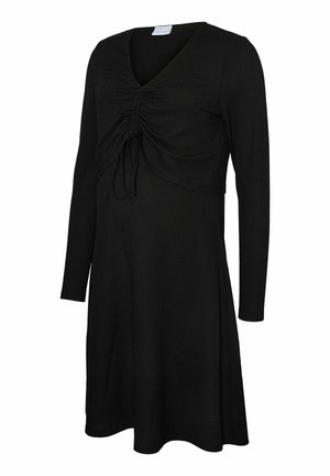 Svart långärmad klänning med V-ringning och draperad tygdetalj vid bysten. Mjuk, texturerad material; flödande A-linjeform.