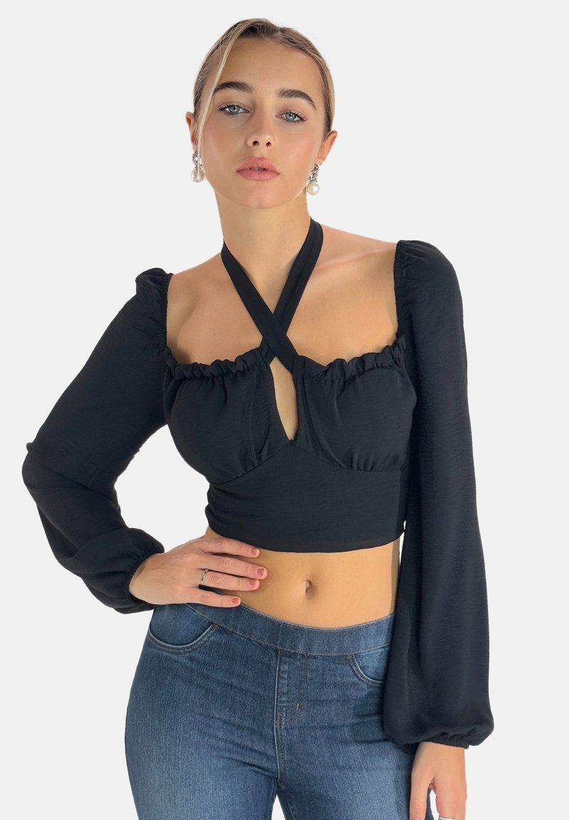 Sort Crop-top med lange puffærmer, rynket udskæring og en fronthul udskæring. Sat sammen med blå denim jeans.
