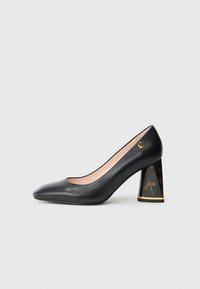 Black leather pump with pointed toe, block heel featuring tortoiseshell pattern and gold trim, and small gold logo near the heel.
