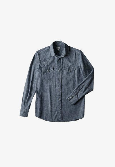 Chemise en denim, bleu foncé, à manches longues, col pointu, deux poches poitrine avec rabats et boutons-pression argentés. Tissu texturé.