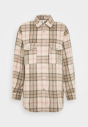 Plaid shirt jacket in beige, brown, and pink. Made of a textured fabric with two chest pockets and silver snap buttons.