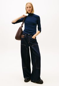 Μπλε ναυτικό ριμπ μπλούζα με μακριά μανίκια και σκούρα μπλε τζιν παντελόνια με φαρδιά πόδια και αντίθετη ραφή. Καφέ τσάντα ώμου, μαύρες πλατφόρμες μπότες και ξεχωριστές λεπτομέρειες στις τσέπες.