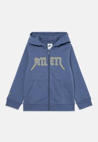 Felpa blu con zip realizzata in tessuto morbido, caratterizzata da un logo frontale giallo, due tasche frontali e un cappuccio dal design semplice.