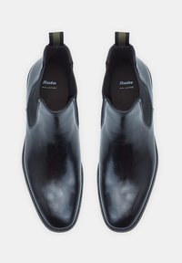 Botas Chelsea de cuero negro con paneles laterales elásticos, tacón plano, punta afilada y tirador de tela. Logotipo "Bata" impreso en el interior.