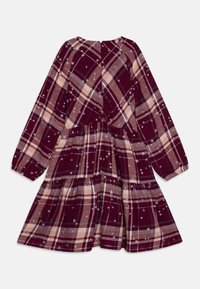 Vinröd klänning i plaid med långa ärmar, med en lager-på-lager-design, stjärndekorationer och rund halsringning. Dragkedja bak.
