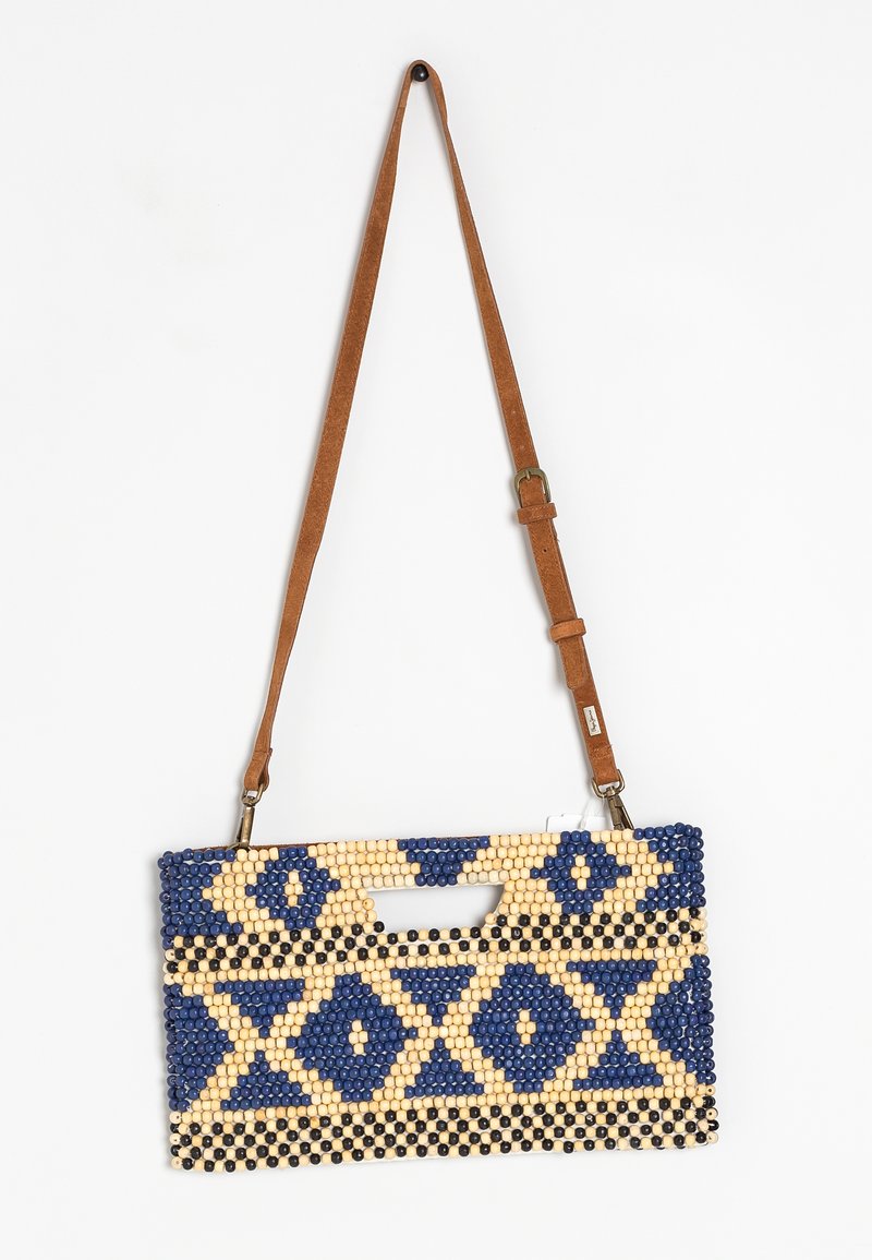 Bolso de mano con cuentas con un patrón geométrico en azul marino, crema y negro. Presenta una correa ajustable marrón y un asa en forma de corte.