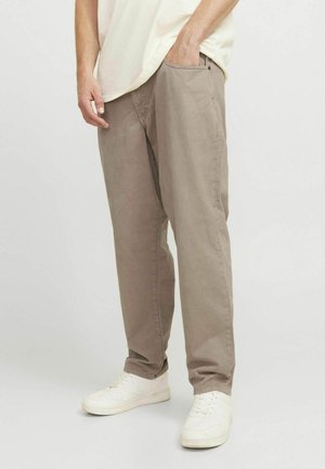 Light brown, relaxed-fit pants made of cotton with a smooth texture, featuring side pockets and worn with white sneakers.