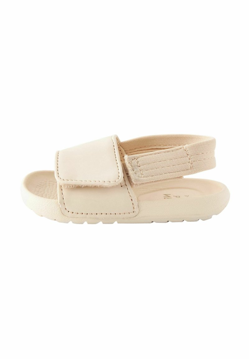 Sandalia beige con una parte superior sintética suave y una correa elástica. Cuenta con un amplio cierre de velcro y una suela de goma texturizada para mayor agarre.