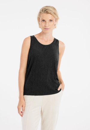 Schwarzes, ärmelloses, geripptes Tanktop aus texturiertem Stoff, mit Rundhalsausschnitt und lockerer Passform, kombiniert mit hellen Hosen.