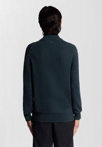 Dunkelblauer Pullover mit hohem Kragen, gerippten Bündchen und Saum, strukturiertem Strickmuster und nahtloser Schulterkonstruktion.