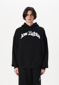 Must nööbikuudiga must kapuutsiga pusakar, millel on eesmine tasku ja valge tikandiga tekst "low lights" rinna piirkonnas. Pehme tekstuur ja mugav lõige.