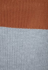 Maglione lavorato a maglia con un design a spacco, con la parte superiore di colore ruggine e la parte inferiore di un grigio chiaro. Strutturato con motivi a coste.