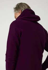 Sudadera con capucha en tejido púrpura oscuro, con un diseño simple, textura suave, puños acanalados y vista trasera que muestra la capucha.