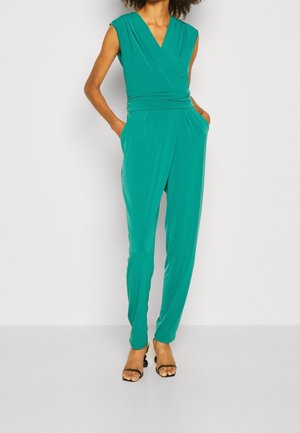Türkisfarbenes Jumpsuit mit V-Ausschnitt, kurzen Ärmeln und tailliertem Schnitt. Besitzt seitliche Taschen und tapered Hosenbeine, hergestellt aus einem glatten, dehnbaren Stoff.