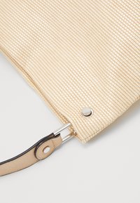 Woven beżowa torba o teksturowanej powierzchni, srebrne okucia oraz brązowy skórzany pasek przymocowany z detalem na zatrzask.