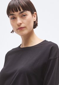 Μαύρο κοντομάνικο μπλουζάκι με στρογγυλή λαιμόκοψη, κατασκευασμένο από απαλό ύφασμα, με άνετη εφαρμογή και μινιμαλιστικό σχέδιο.