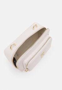 Bolsa de color rosa claro con cremallera, herrajes en tono dorado, dos compartimentos y un acento de logo; textura suave y forma rectangular.