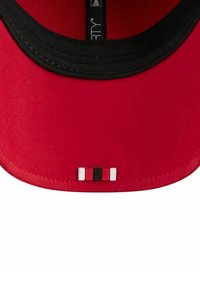 Casquette rouge avec une visière noire et un accent décoratif en blocs rouges, noirs et blancs à l'intérieur. Fabriquée à partir d'un tissu texturé.