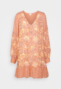 Langærmet, ferskenfarvet kjole med blomsterprint, V-hals, knapdetaljer, sammensatte manchetter og flæset kant mod en ensfarvet baggrund.