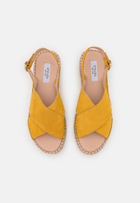 Yellow suede espadrille sandals featuring cross strap design, open toe, and woven jute sole with a light brown insole. Buckle closure on the side.