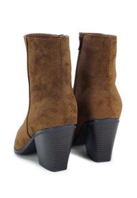 Bruine suède enkellaarsjes met een hoge hak, met een gladde textuur, verticale naden en een zijrits voor gemakkelijk aan- en uittrekken.