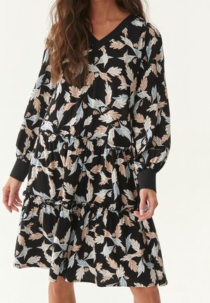 Robe noire à manches longues, décolleté en V, design à volants en étages, arborant un motif floral avec des feuilles beiges et bleues. Texture de tissu lisse.