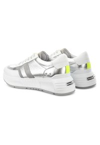 Weiße und silberne Plateau-Sneaker mit grauen Akzenten und gelben Fersenstreifen, von hinten und seitlich auf weißem Hintergrund betrachtet.