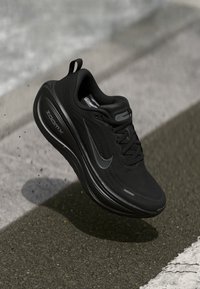 Svarta Nike ZoomX-sneakers med en texturerad övre del, snörning och reflekterande detaljer, som har en kraftig sula för dämpning.