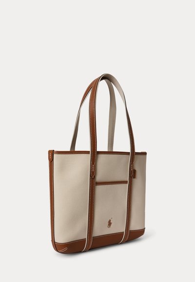 Sac cabas en toile beige avec garniture en cuir marron, longues anses, poche avant et petit logo brodé d'un joueur de polo.