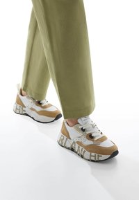 Chunky sneakers with a white leather upper, tan suede accents, and black rubber sole; features bold "BLANCHE" lettering on the sides.