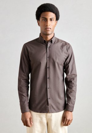 Camicia a maniche lunghe, con bottoni, in tessuto marrone scuro. Presenta un colletto appuntito, una patta frontale con bottoni e maniche aderenti.