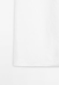 Tissu en coton blanc avec une texture lisse, présentant une bordure droite en bas et un design sans couture. Aucun motif ou détail visible.