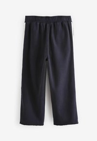 Pantaloni della tuta a gamba larga blu navy in morbido tessuto, con vita elastica e strisce laterali bianche. Dettaglio a taglio vivo sull'orlo delle maniche.